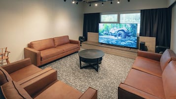 Moderni olohuone, jossa on ruskea nahkasohva, sohvapöytä ja seinälle asennettu litteänäyttöinen televisio. Seinä on tehty puusta.