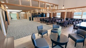 Un hall d’hôtel spacieux avec un grand espace ouvert, de nombreux coins salon et un coin cuisine à l’arrière-plan.
