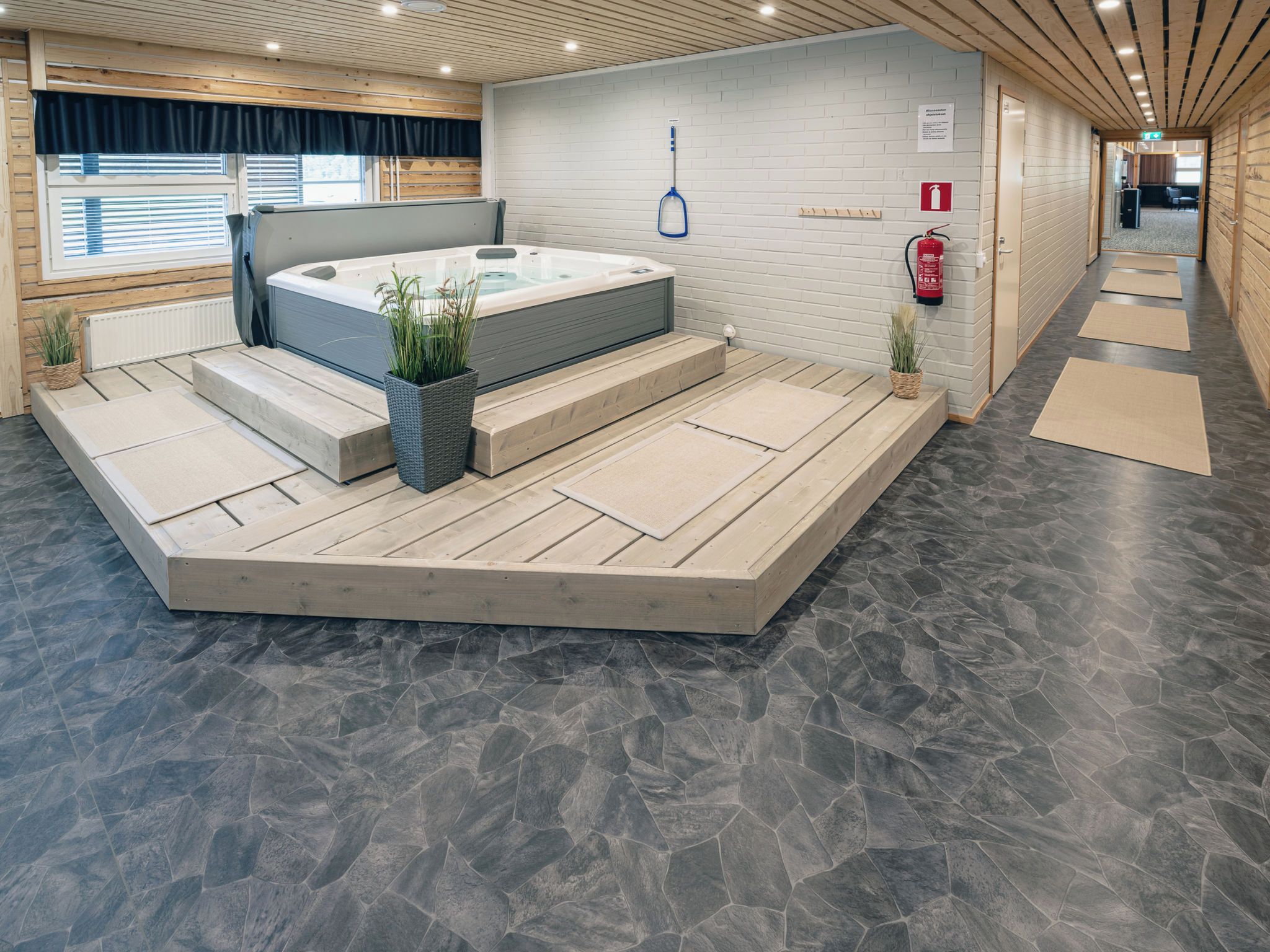 Un espace spa moderne doté d’un jacuzzi, d’un plancher en bois et d’un extincteur fixé au mur.