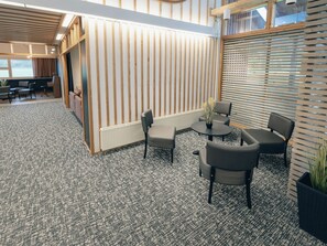 A modern interior with a seating area, a reception desk, and a large window.