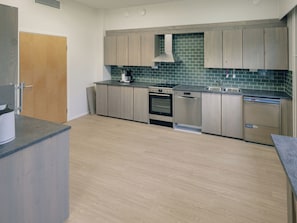 Une cuisine moderne avec des meubles en bois clair, un four en acier inoxydable et un lave-vaisselle.