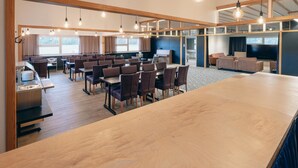 Une salle de conférence spacieuse, dotée d’une longue table et de chaises, d’un espace buffet et d’un grand écran pour les présentations.