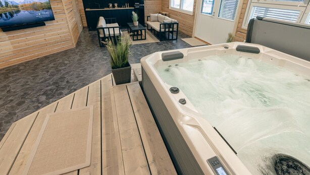 Un espace spa comprenant un jacuzzi, un plancher en bois, une télévision et un coin salon offrant une vue sur les montagnes.