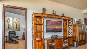 Una sala de estar con un mueble de madera para centro de entretenimiento, un sillón de cuero negro y un televisor grande.
