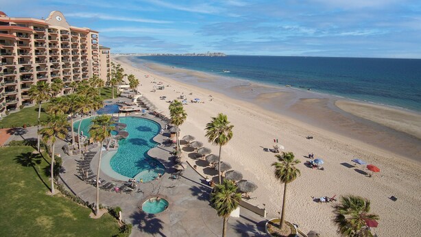 Un resort con una piscina grande, playa y vista al océano.