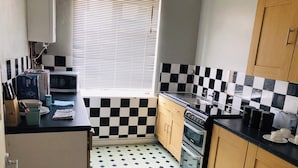 A kitchen with black and white checkered tiles, a microwave, an oven, and a sink.