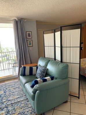 Relax in this inviting living area with a sofa, table, and balcony access.