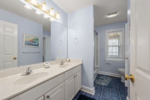 A bathroom with two sinks, a large mirror, and a shower area.