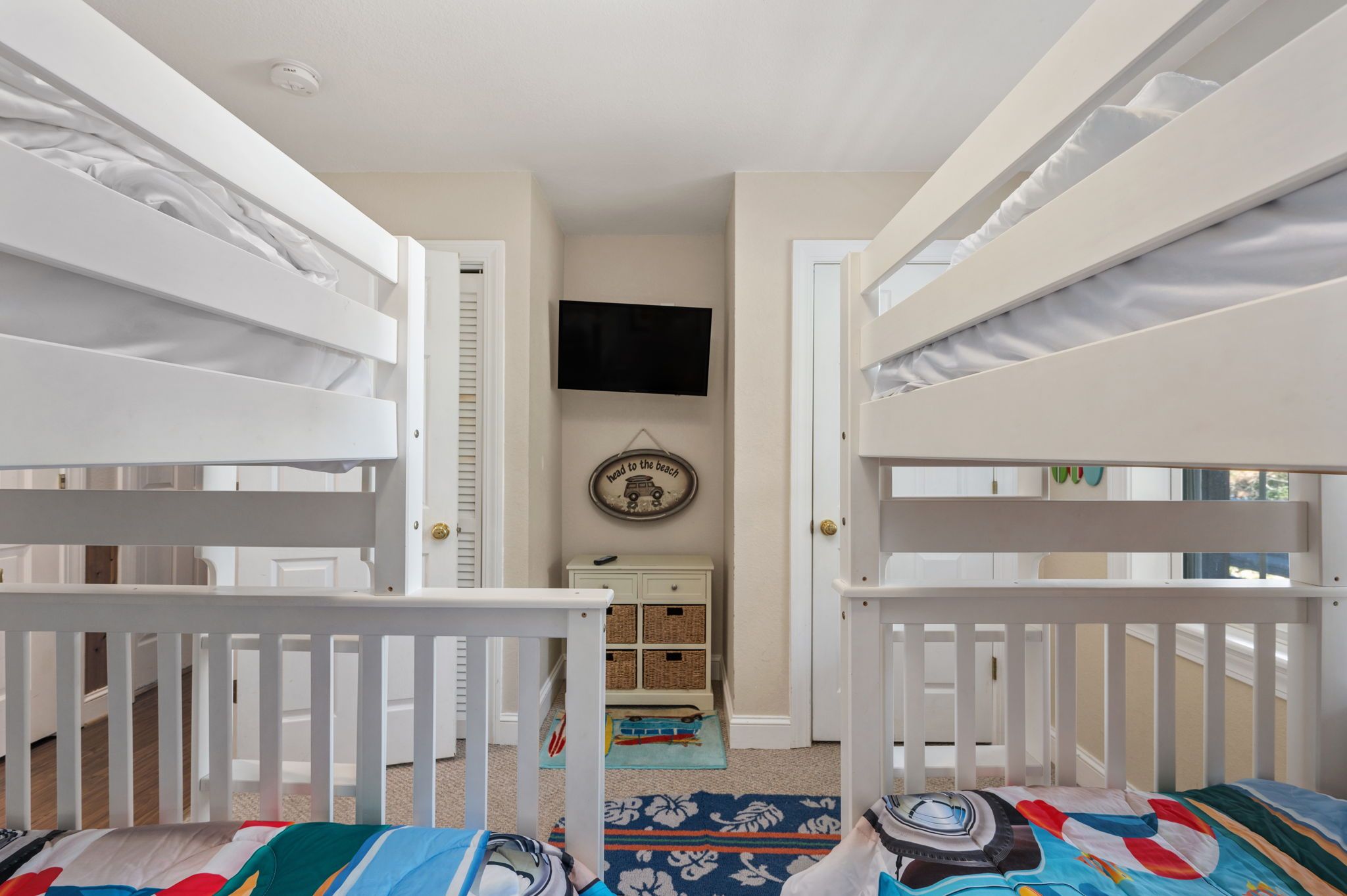 Een slaapkamer met stapelbedden, een televisie aan de muur en een kleine dressoir met lades.