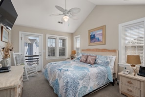 A bedroom with a bed, a desk, a chair, a ceiling fan, and a window with blinds.