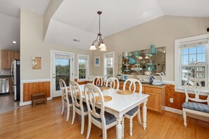 A spacious kitchen with a dining area, wooden floors, and a view of the outdoors.