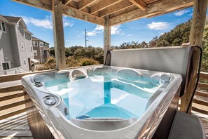 A hot tub under a wooden pergola with a clear view of the surrounding residential area.