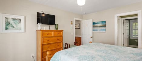 A bedroom with a bed, a dresser, a television, and a ceiling fan.