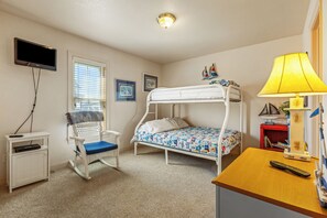 Une chambre avec un lit superposé, une télévision, un fauteuil à bascule, un bureau et une lampe.