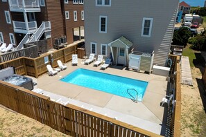 A backyard with a swimming pool, lounge chairs, and a wooden deck.