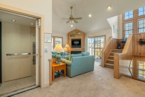 A spacious living area with a blue sofa, a wooden staircase, and a ceiling fan.