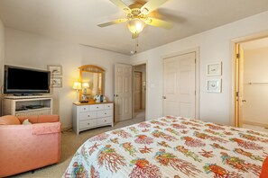 A bedroom with a bed, a television, a dresser, a mirror, and a ceiling fan. - Carolina Dreamin: Semi-oceanfront, pool, hot tub, ocean views, elevator! (Kill Devil Hills)