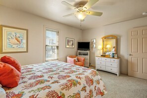 A bedroom with a bed, a ceiling fan, a TV, a dresser, and a window with blinds.