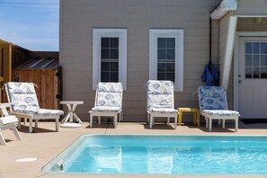 Un espace aménagé au bord de la piscine, avec des chaises longues et une piscine.