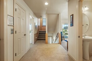 Un couloir doté de revêtements de sol en moquette, de portes blanches et d’un escalier menant à un niveau supérieur.