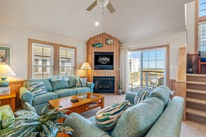 A living room with a fireplace, a television, and a balcony with a view.