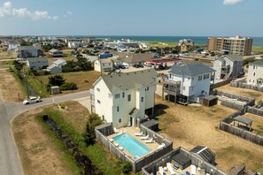 Un quartier résidentiel avec des maisons, une piscine et une plage en arrière-plan.