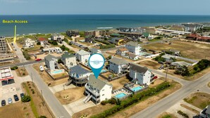 Vue aérienne d’une zone résidentielle côtière, avec des maisons, une station-service et un point d’accès à la plage.
