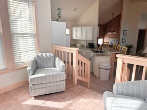 A compact living space with a kitchenette, a dining area, and a seating area with a small wooden railing.