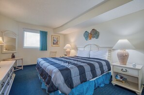 Une chambre d’hôtel avec un grand lit, des tables de chevet, une commode et une fenêtre avec des rideaux.