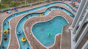 A pool area with multiple lanes and inflatable rings, adjacent to a beach with umbrellas and lounge chairs. - Oceanfront 1BD-Baywatch Resort-Family Friendly (North Myrtle Beach)