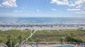Une plage avec des parasols et des chaises longues, un ciel dégagé et une vue sur l’océan.