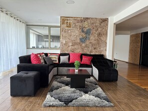 Un salon moderne avec un canapé d’angle, une table basse et un tapis à motifs.