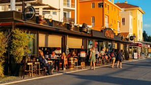 A lively outdoor café with tables and chairs, a Guinness sign, and a '49's Hole' sign.