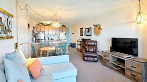 Un salon moderne comprenant un canapé, un téléviseur et un coin repas avec des chaises et une table.