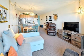 A modern living room with a sofa, TV, and a dining area with chairs and a table.
