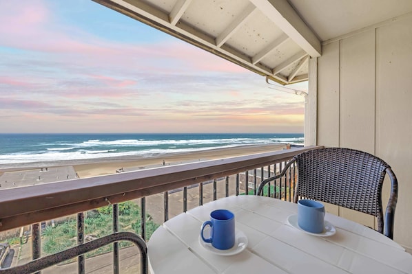 Un balcón con mesa y sillas con vista a la playa.