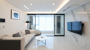 Un salon moderne avec un canapé, une table basse et un téléviseur à écran plat fixé au mur.