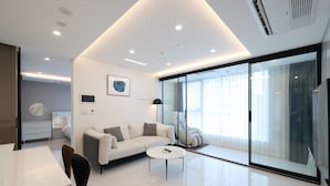 Un salon moderne avec un canapé blanc, une table basse et une cloison en verre.