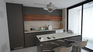 Une cuisine moderne avec des meubles de couleur sombre, un îlot en marbre et une grande fenêtre.