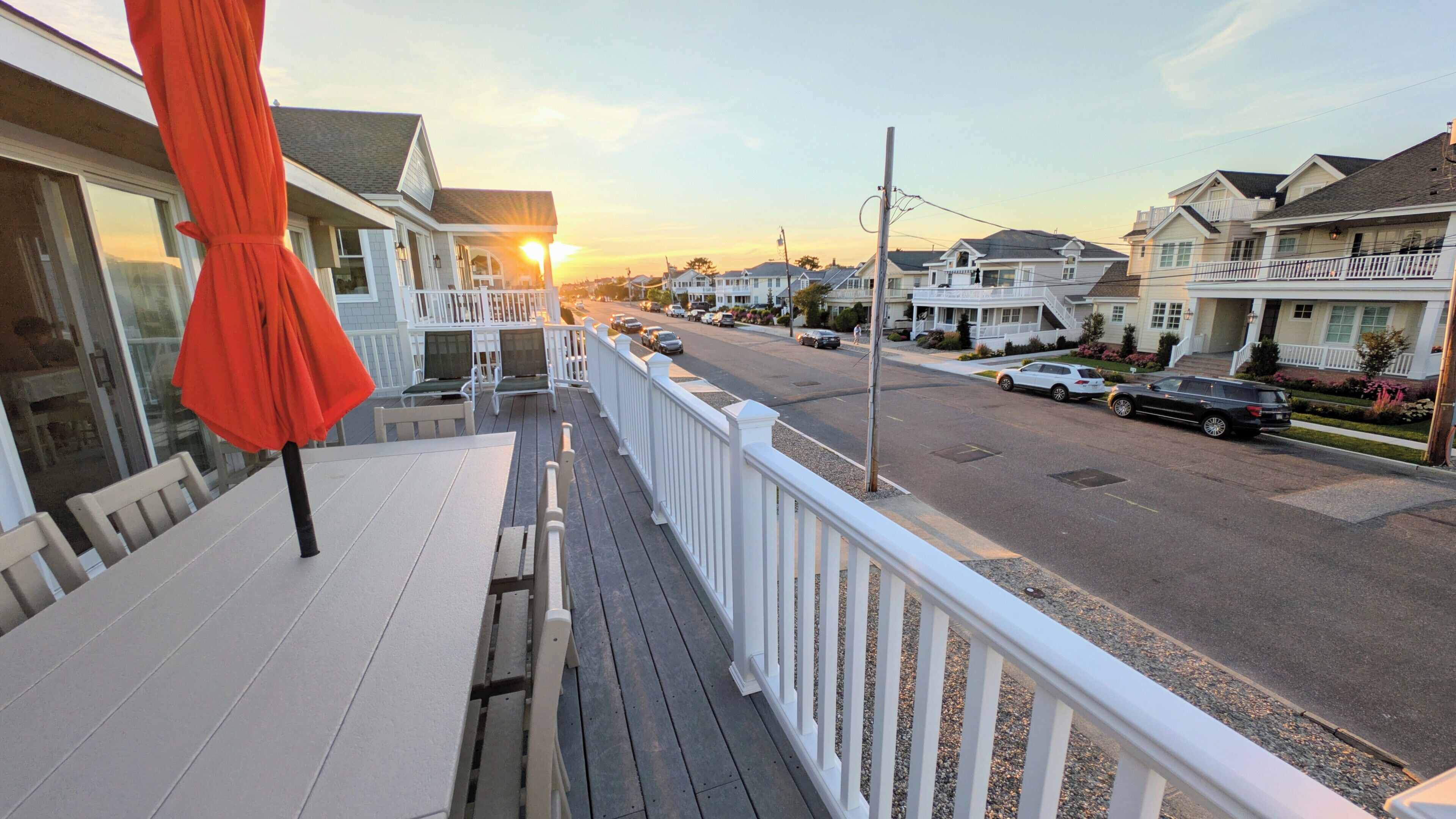 A residential street with houses, a clear sky, and a sunset.