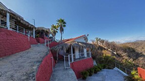 A hotel with a red exterior, a thatched-roof structure, and a view of the surrounding landscape.