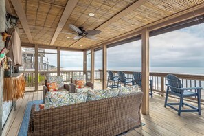 A covered outdoor seating area with wicker furniture, a ceiling fan, and a view of the ocean. - BEACH FRONT gathering spot for family, friends and pups. WINTER RATES AVAILABLE! (Alligator Point)