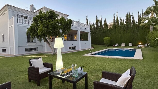 Une maison moderne dotée d’une piscine, de mobilier d’extérieur et d’une pelouse bien entretenue.