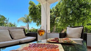 Un espace de restauration en plein air avec un plateau de fruits de mer, un verre de bière et un canapé avec des coussins.