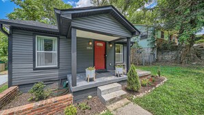 A two-story house with a red door, numbered 1804, and a covered porch with potted plants. - Nashville Charmer (Nashville)