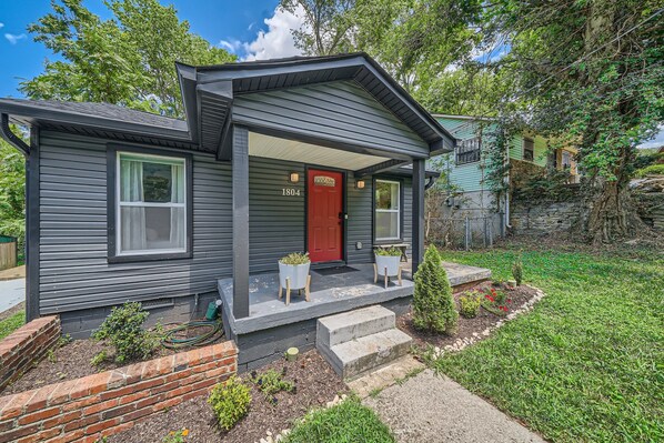 A two-story house with a red door, numbered 1804, and a covered porch with potted plants. - Nashville Charmer (Nashville)