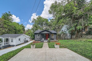 A single-story house with a dark front door, a small porch, and a front yard with a pathway leading to the entrance. - Nashville Charmer (Nashville)