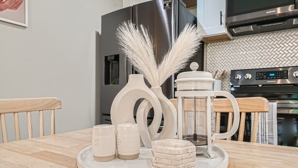 A kitchen with a wooden table, white ceramic salt and pepper shakers, a white ceramic pitcher, and decorative feathers. - Nashville Charmer (Nashville)