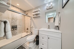 A modern bathroom with a glass-enclosed shower, a toilet, and a white vanity with drawers. - Nashville Charmer (Nashville)
