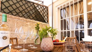 A wooden table set with wine glasses, a bottle of wine, a potted plant, and a basket of fruit. - Beautiful Holiday Home in Costa Adeje with partial sea view (Adeje)